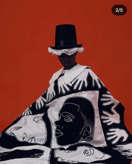 Patchwork quilt (black and white hands and faces)  worn by a stunning African woman wearing iconic Welsh hat