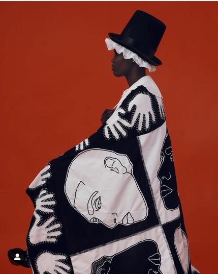 Patchwork quilt (black and white hands and faces)  worn by a stunning African woman wearing iconic Welsh hat