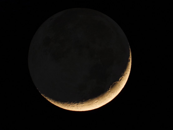 The crescent moon with the shadowed part slightly illuminated by earthshine