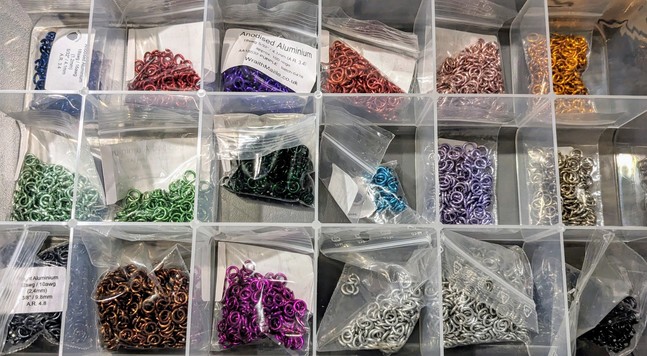 A box of colourful jump rings in a divided clear plastic box