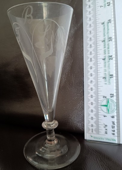 A Georgian 'Short ale' glass. It was made in 3 parts: bowl, stem and foot which were formed separately and then put together. Engraved with barley and hops to show it's use and with the owners initials, BJS. The engraving was done by holding the glass against a rotating abrasive wheel.