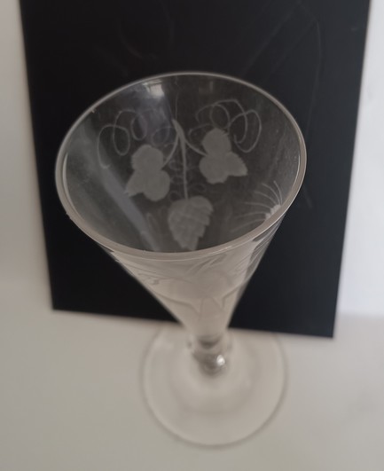 The same glass, photographed from above and against a black background to show the engraved hop flower, leaves and tendrils.