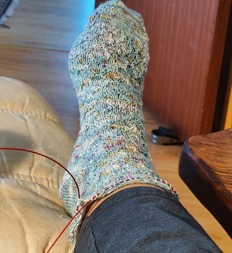 Partially knitted sock on my foot. Colour -speckled light blue 