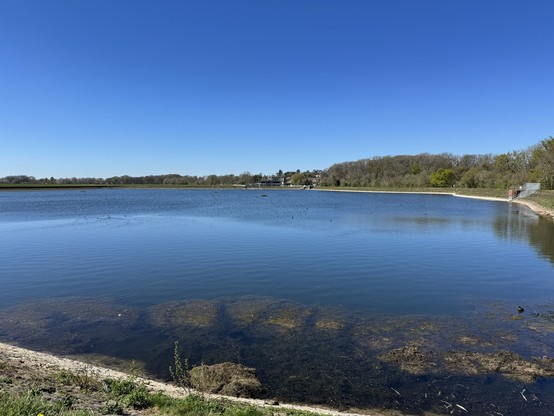 Sweeping view across blue reservoir reflecting cloudless deep blue sky