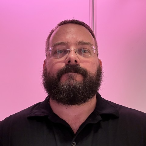 Me, looking direct to camera with a pink illuminated wall behind me