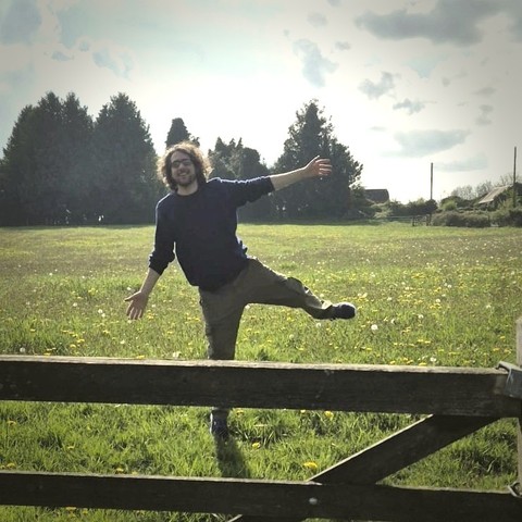 Chris happily dancing around in a green meadow on a sunny day.