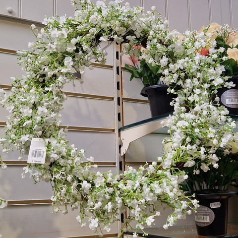 A plastic wreath of lot of little white flowers on light green stems.