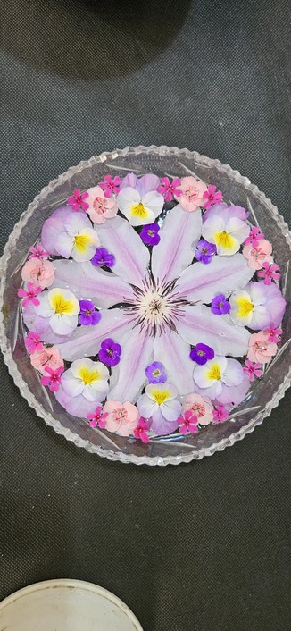 Floral display comprising clematis Nelly Moser, pinks, aubtetia, violas and phlox flowers.