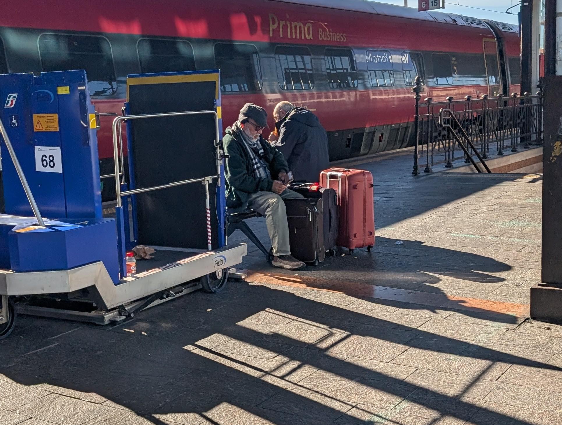 Two gentlemen in Verona, sitting on the train platform