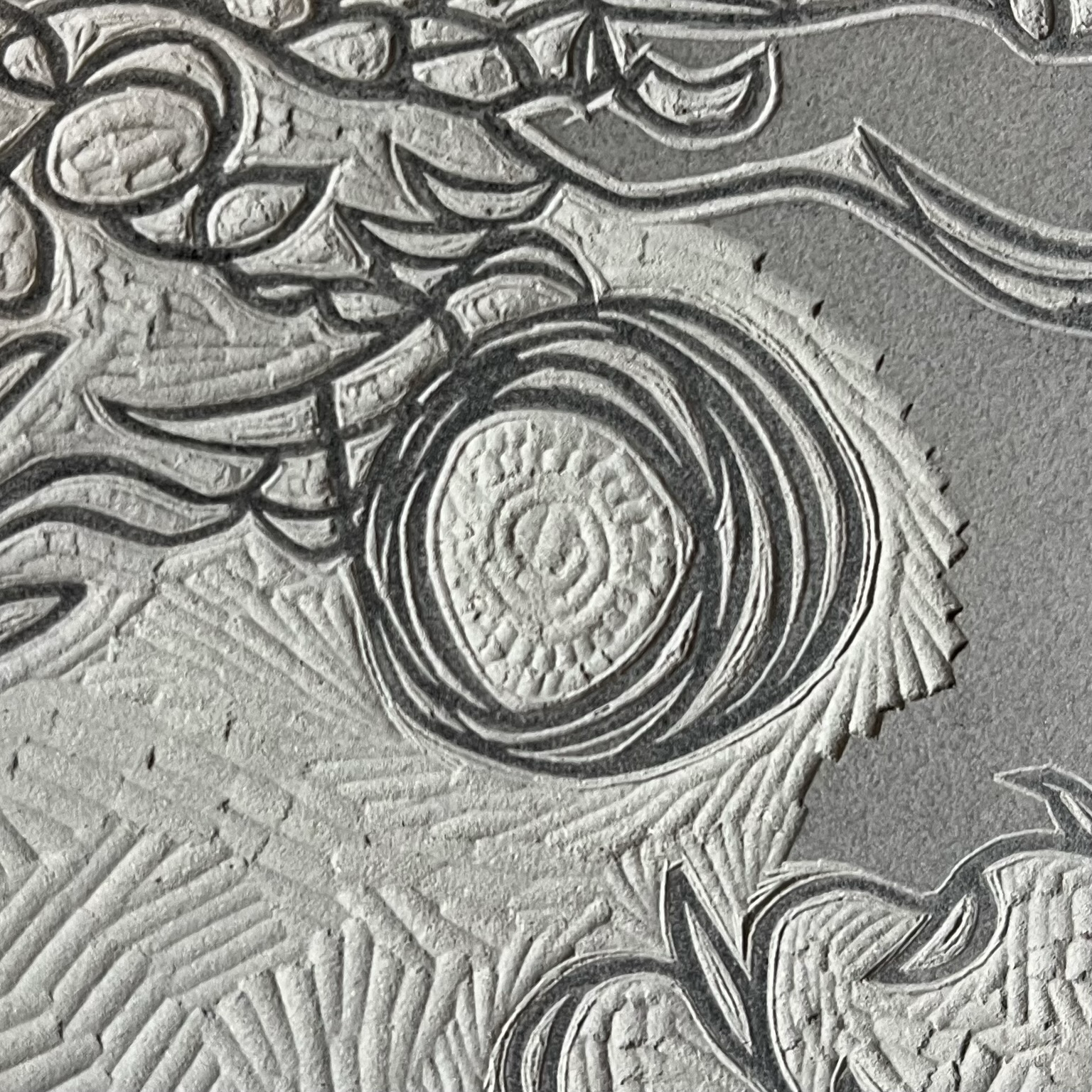 Detail from a partially carved lino block showing marks made by the gouge when cutting around lines and removing the surface.
