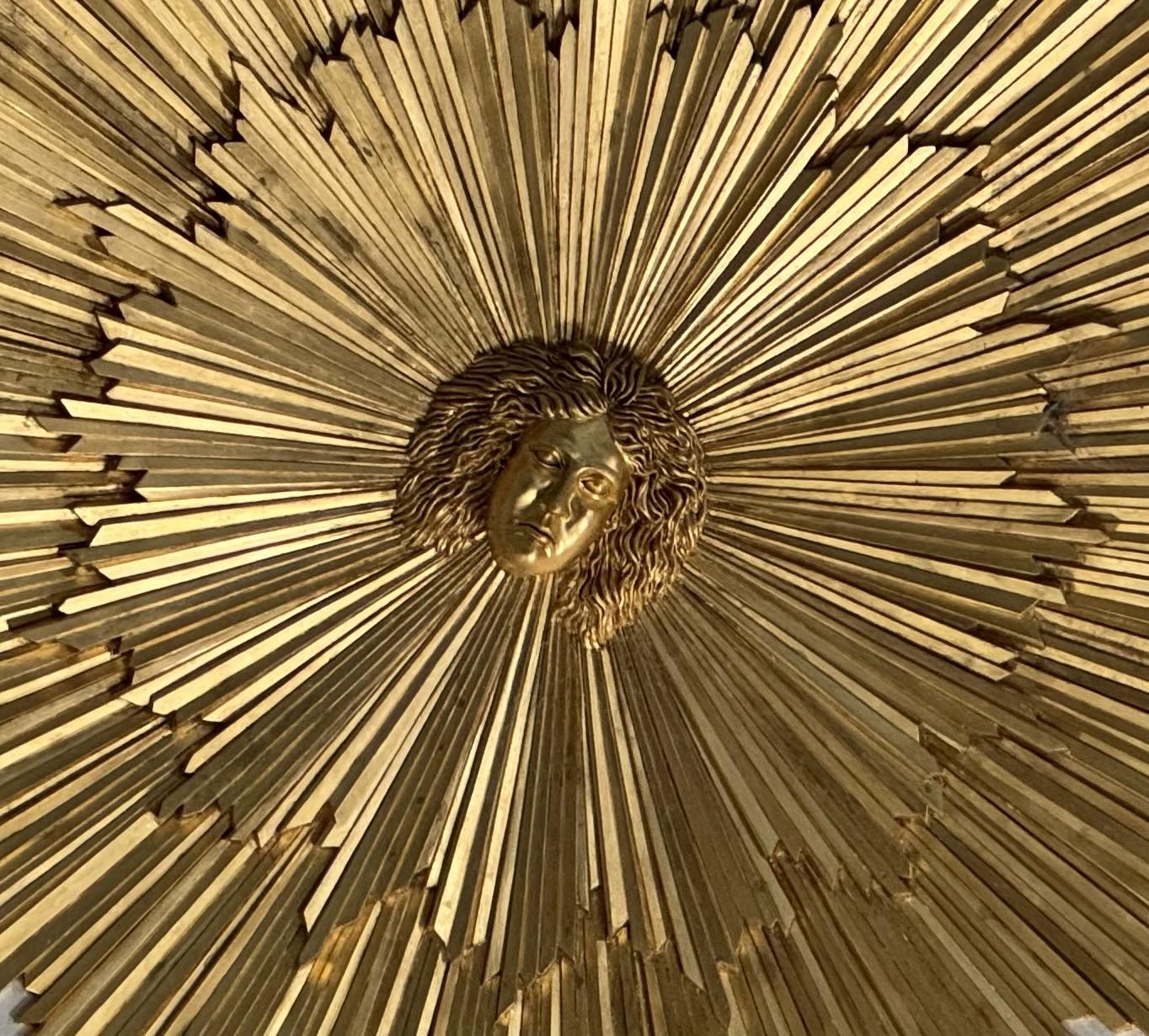 Close up of stylised gold sunburst with face of the god Apollo in the middle. This is the ceiling centre piece of the Temple of Apollo in the grounds of Stourhead House, UK