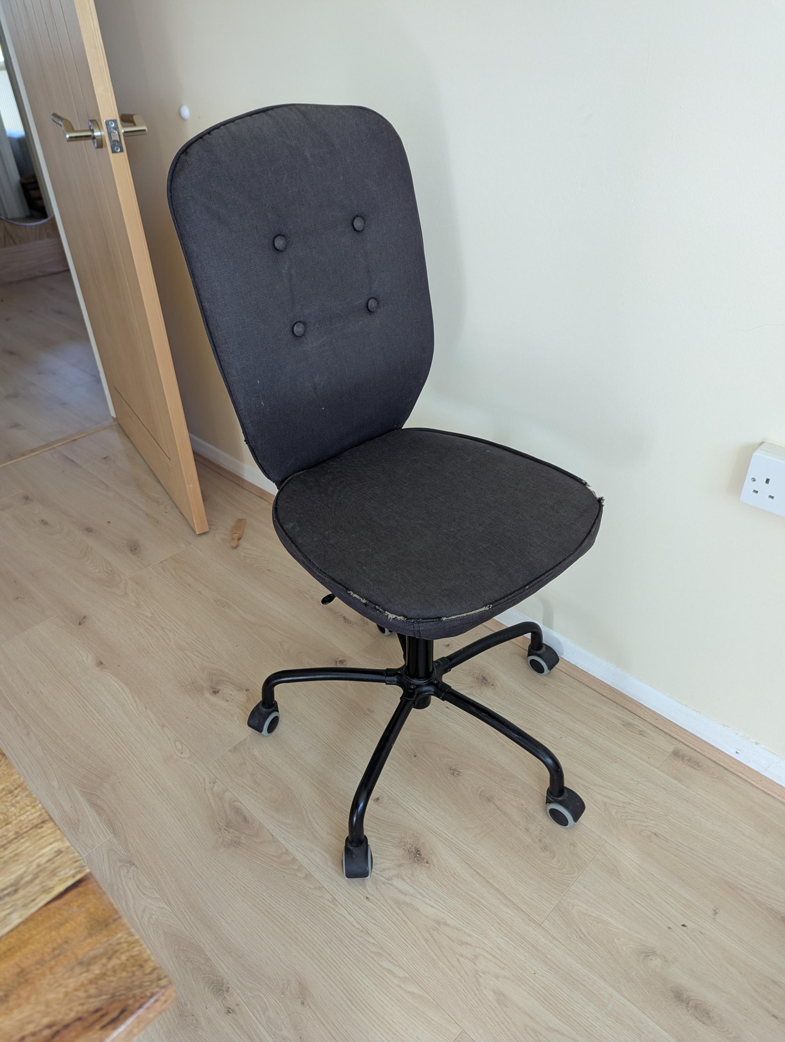 A desk chair with a black cover and black legs.