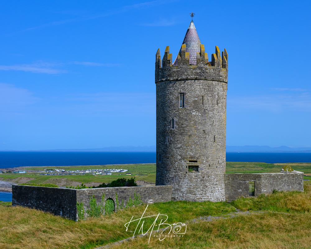 Interesting circular small castle, overlooking the Atlantic Ocean. It has a conical roof, and a series of pediments around the top. There is a wall extending to the left and right beyond the base. All appear fairly well maintained, but it does not appear to be inhabited.