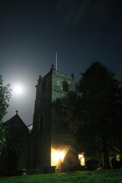 A square church tower against a clear starlit sky and the full moon 